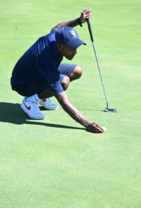 N. Davids lining up a putt during the SA Navy Championships, carefully aligning the ball on the green before taking the shot.